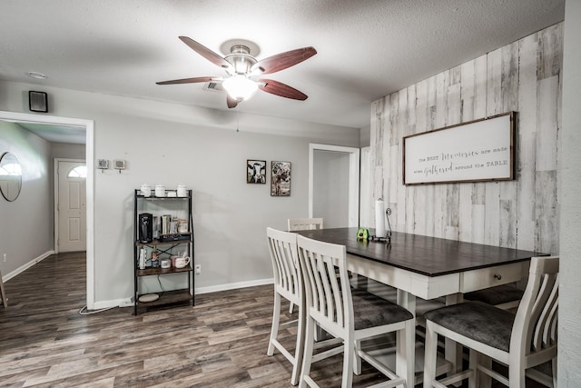 dining area featuring wooden walls, dark hardwood / wood-style flooring, and ceiling fan