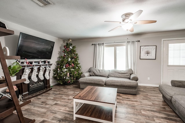 living room with ceiling fan, wood-type flooring, and a textured ceiling