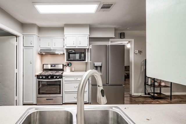 kitchen with stainless steel appliances, white cabinetry, dark wood-type flooring, and sink