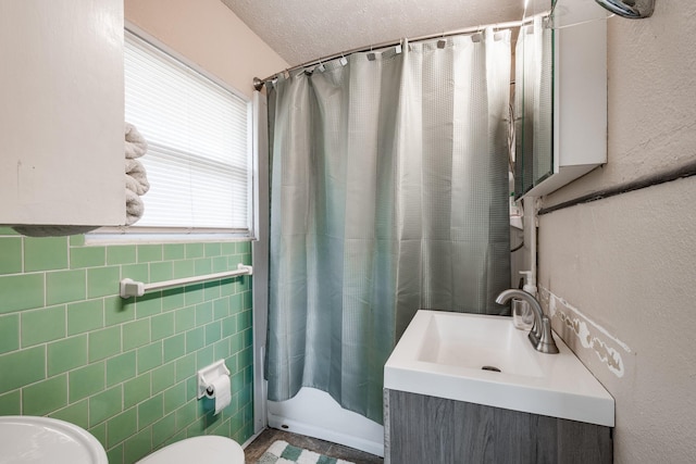 full bathroom featuring vanity, toilet, a textured ceiling, tile walls, and shower / tub combo