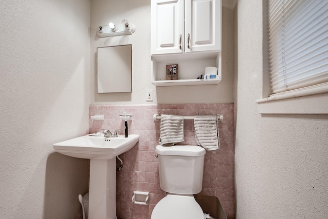 bathroom featuring toilet and tile walls