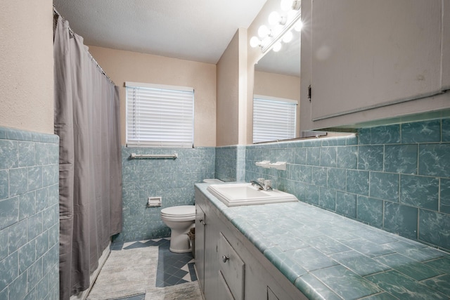 bathroom featuring vanity, tile walls, and toilet