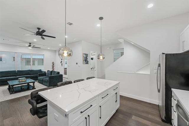 kitchen with appliances with stainless steel finishes, dark wood-type flooring, decorative light fixtures, a center island, and white cabinetry