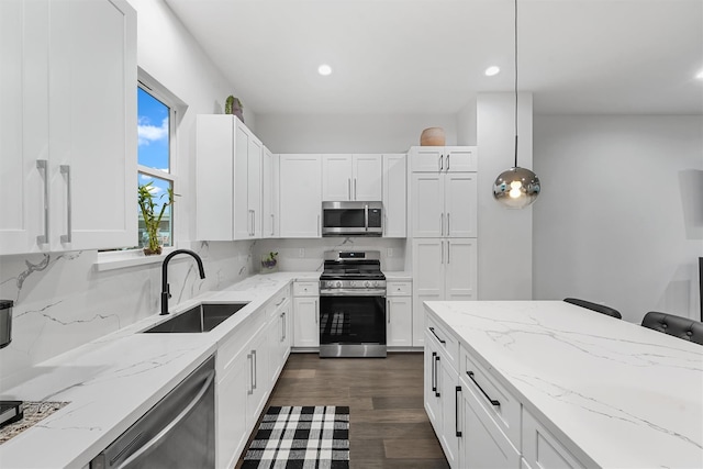 kitchen with decorative light fixtures, sink, white cabinetry, and stainless steel appliances