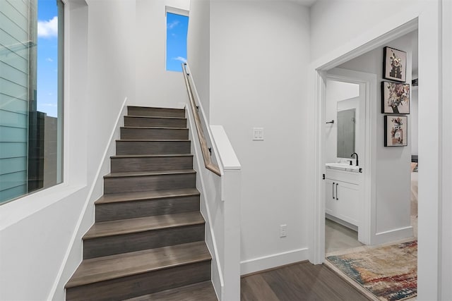 stairs with sink, a healthy amount of sunlight, and wood-type flooring