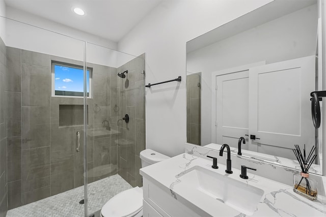 bathroom with a shower with door, vanity, and toilet