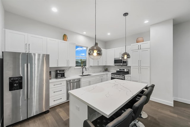 kitchen with sink, dark hardwood / wood-style floors, light stone countertops, decorative light fixtures, and stainless steel appliances