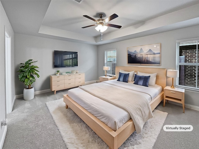 carpeted bedroom featuring a raised ceiling and ceiling fan