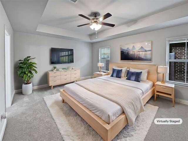 carpeted bedroom featuring a raised ceiling and ceiling fan