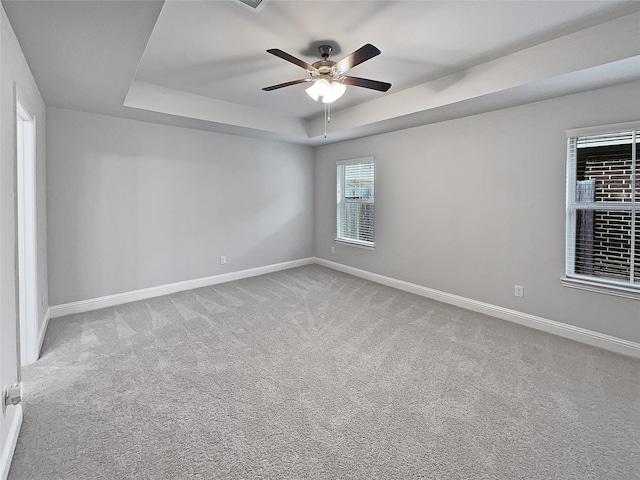 carpeted empty room with ceiling fan and a tray ceiling