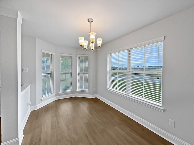 unfurnished room with a healthy amount of sunlight, a notable chandelier, and hardwood / wood-style flooring