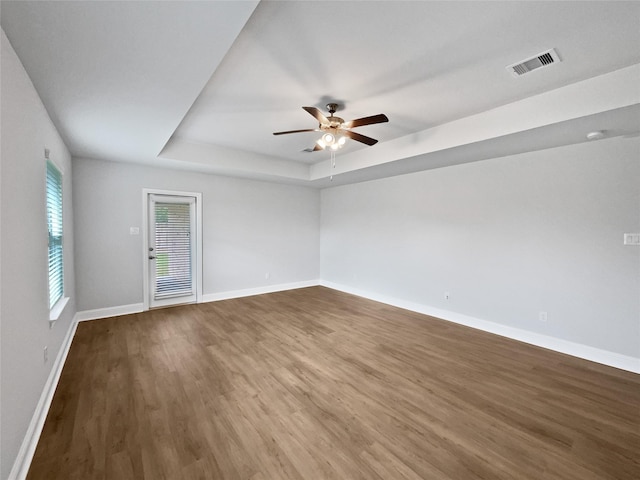 unfurnished room with hardwood / wood-style flooring, ceiling fan, and a raised ceiling