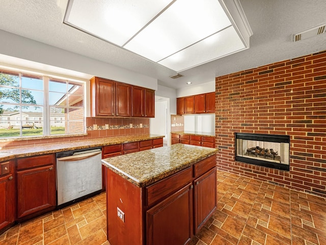 kitchen featuring dishwasher, a brick fireplace, light stone counters, a textured ceiling, and a kitchen island