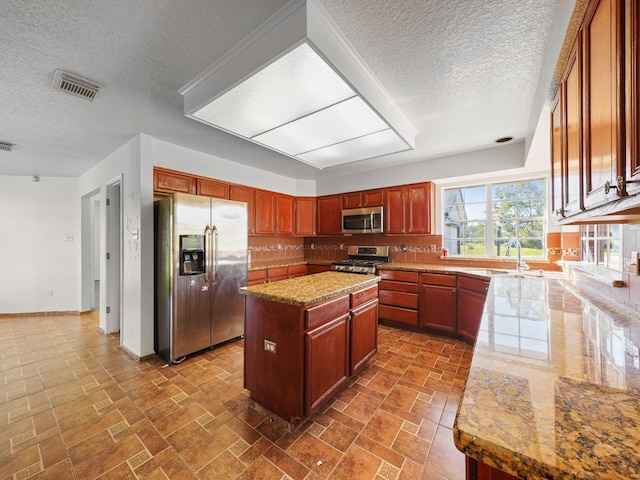 kitchen featuring appliances with stainless steel finishes, tasteful backsplash, a kitchen island, and plenty of natural light