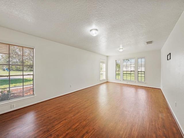 spare room featuring wood-type flooring and a textured ceiling