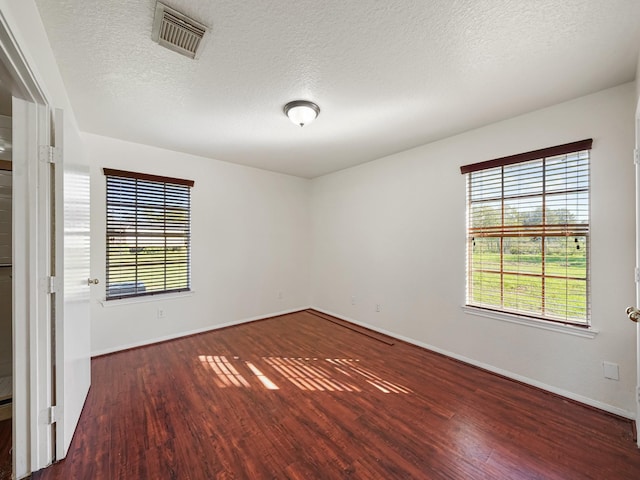 spare room with a textured ceiling and dark wood-type flooring