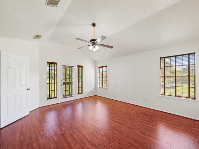 empty room featuring ceiling fan, a healthy amount of sunlight, wood-type flooring, and vaulted ceiling