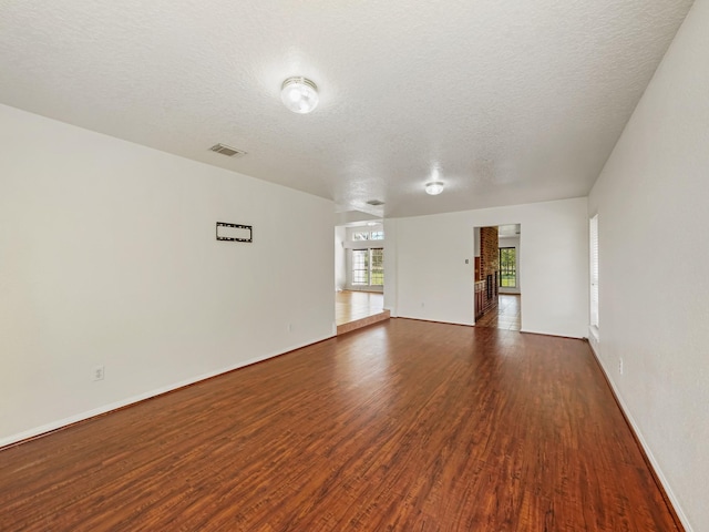 spare room with a textured ceiling and dark hardwood / wood-style floors