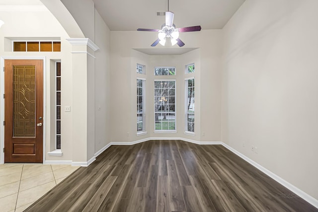 empty room featuring dark hardwood / wood-style floors, ceiling fan, and ornate columns