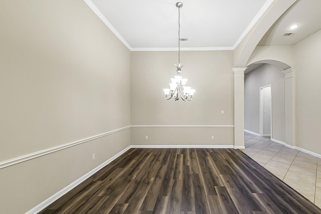 spare room with decorative columns, crown molding, dark hardwood / wood-style flooring, and a notable chandelier