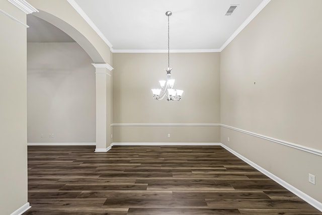 empty room with a chandelier, dark hardwood / wood-style floors, decorative columns, and ornamental molding