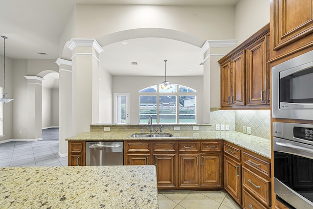 kitchen with light stone countertops, sink, hanging light fixtures, and stainless steel appliances