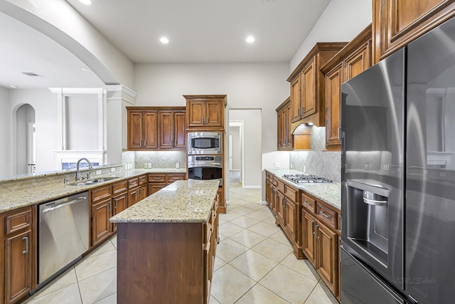 kitchen featuring light stone countertops, a center island, stainless steel appliances, and sink