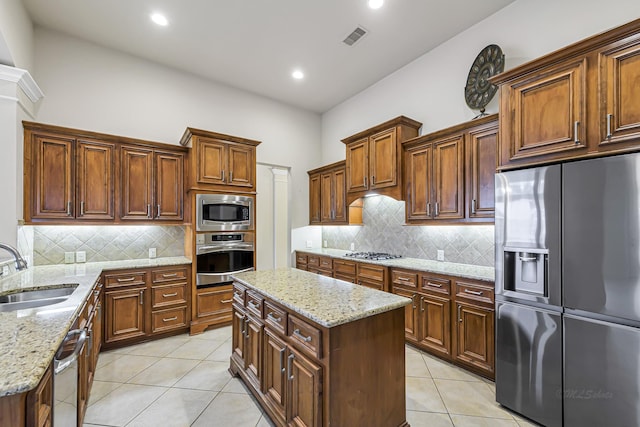 kitchen with light stone counters, sink, a kitchen island, and appliances with stainless steel finishes