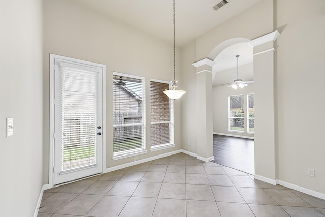 unfurnished dining area with ornate columns, ceiling fan, plenty of natural light, and light tile patterned floors