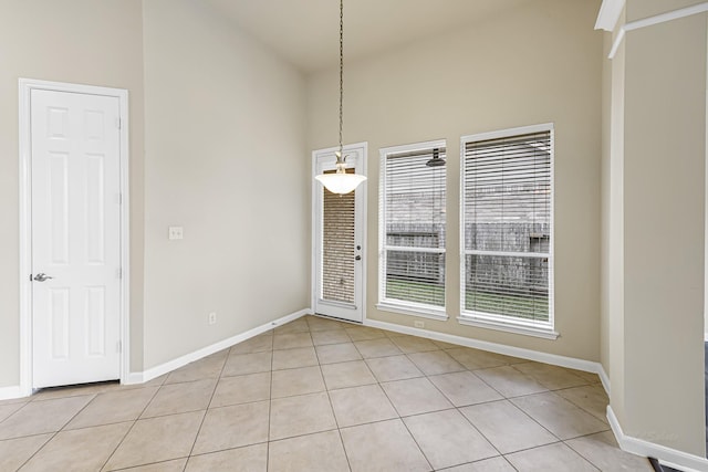 unfurnished dining area featuring plenty of natural light, light tile patterned flooring, and a high ceiling