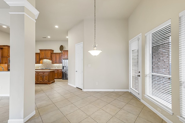 kitchen with tasteful backsplash, stainless steel fridge, light tile patterned flooring, and decorative light fixtures