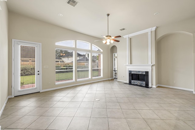 unfurnished living room featuring ceiling fan, a high end fireplace, and light tile patterned floors