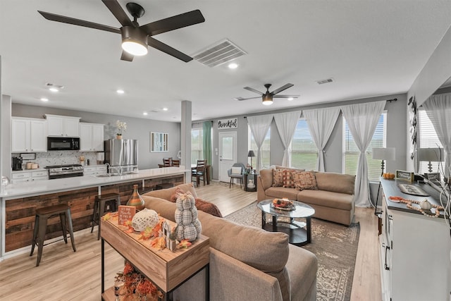 living room with ceiling fan, light hardwood / wood-style floors, a wealth of natural light, and sink