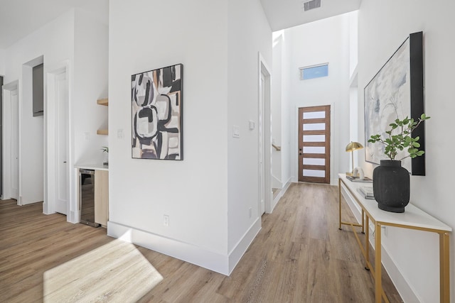 entrance foyer featuring a high ceiling, beverage cooler, and light hardwood / wood-style flooring