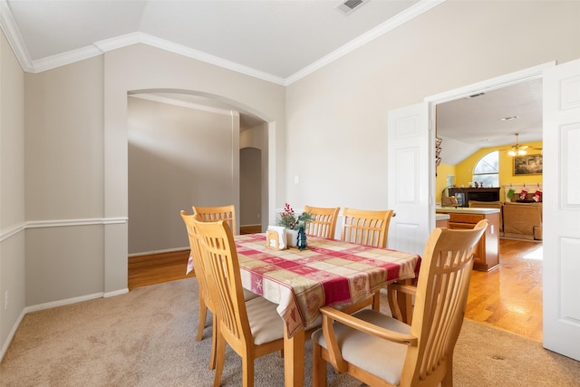 dining space featuring light hardwood / wood-style floors, crown molding, and vaulted ceiling