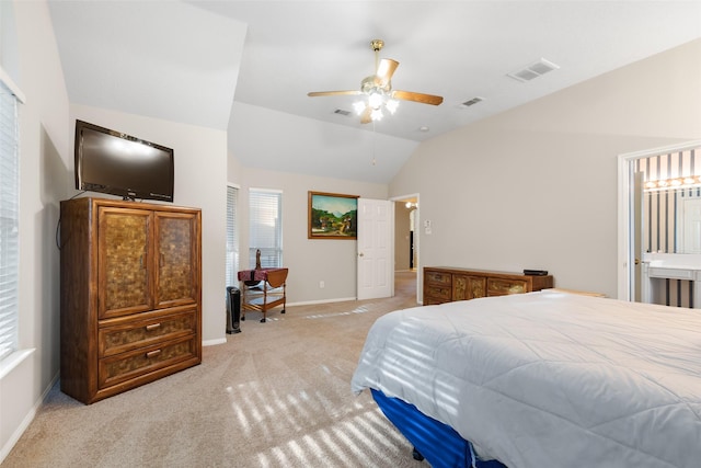 bedroom featuring ceiling fan, vaulted ceiling, light carpet, and ensuite bath