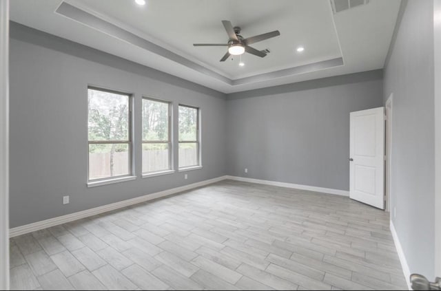 spare room featuring ceiling fan, a raised ceiling, and light hardwood / wood-style flooring