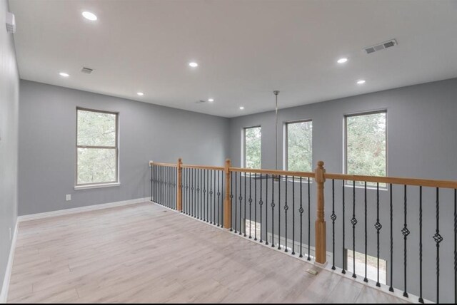 spare room featuring a wealth of natural light and light hardwood / wood-style floors