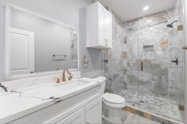 bathroom with hardwood / wood-style flooring, vanity, a shower with shower door, and toilet