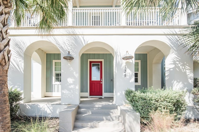 view of exterior entry with a balcony and a porch