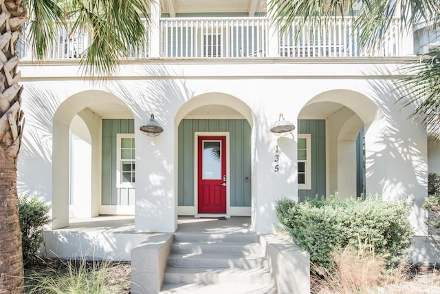 property entrance featuring a balcony, a porch, and stucco siding