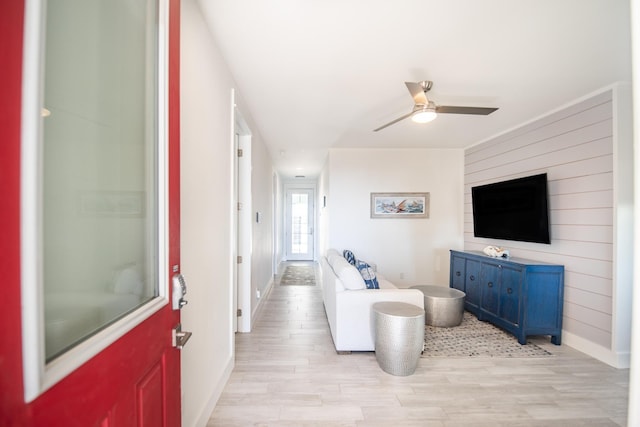 living room with baseboards, ceiling fan, and light wood-style floors