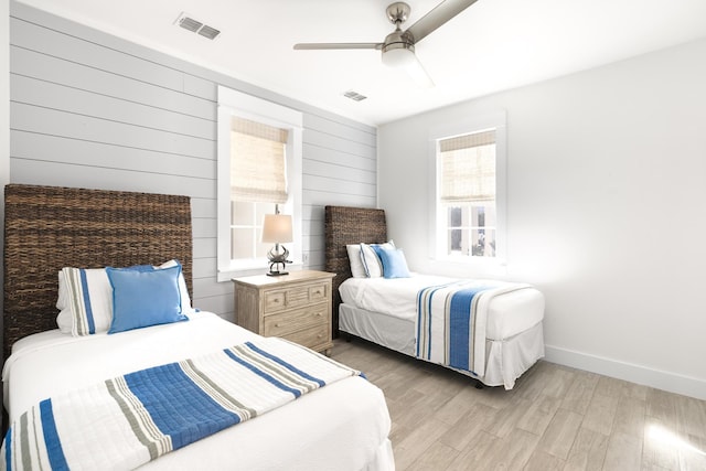 bedroom featuring wooden walls, light hardwood / wood-style floors, and ceiling fan