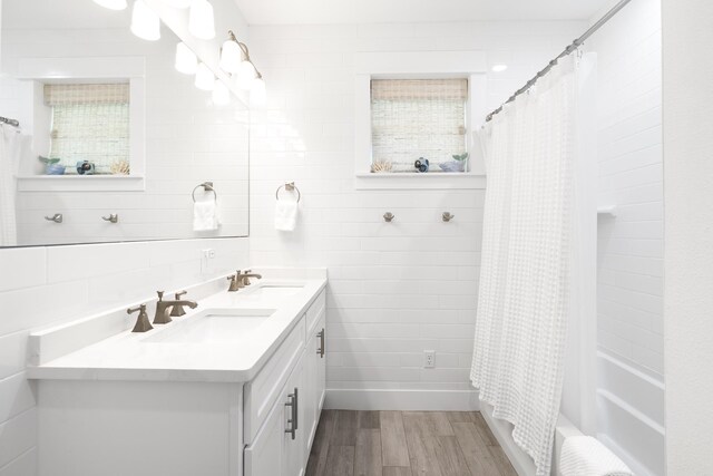 bathroom with shower / bathtub combination with curtain, tile walls, vanity, tasteful backsplash, and wood-type flooring