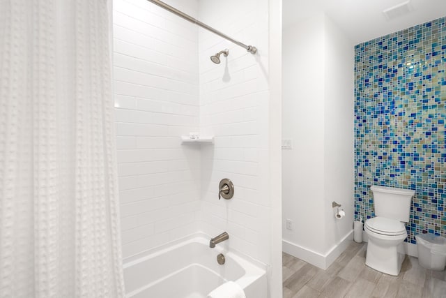 bathroom with visible vents, baseboards, wood finished floors, toilet, and shower / bath combination with curtain