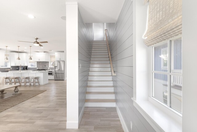 staircase featuring wood-type flooring, sink, and ceiling fan