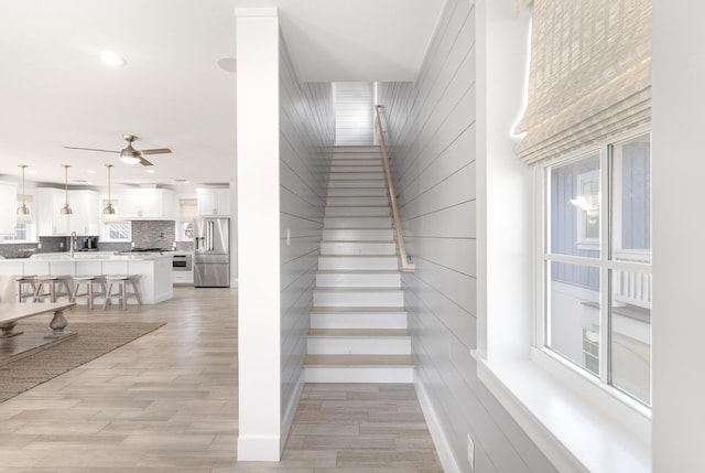 stairs featuring wood finished floors, ceiling fan, and recessed lighting