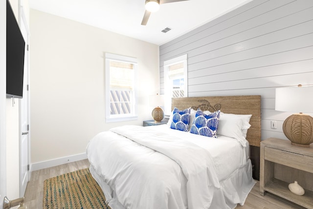 bedroom featuring wood walls, ceiling fan, and light wood-type flooring