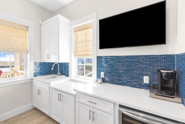 kitchen with tasteful backsplash, light hardwood / wood-style floors, sink, and white cabinets