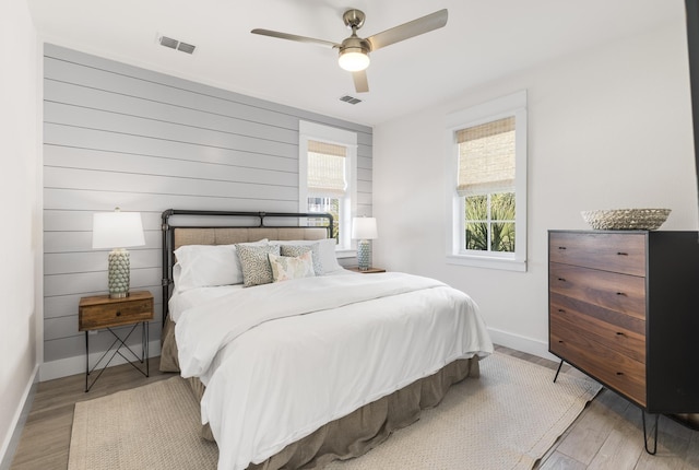 bedroom featuring wood finished floors, baseboards, ceiling fan, and visible vents